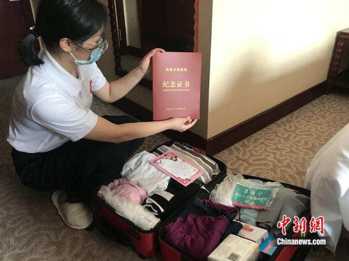 3月17日,中南大学湘雅二医院的医疗队员收拾行李,准备从武汉撤离。队员李佳宁展示行李箱中的纪念证书。 冉文娟 摄 3月17日,中南大学湘雅二医院的医疗队员收拾行李,准备从武汉撤离。队员李佳宁展示行李箱中的纪念证书。 冉文娟 摄