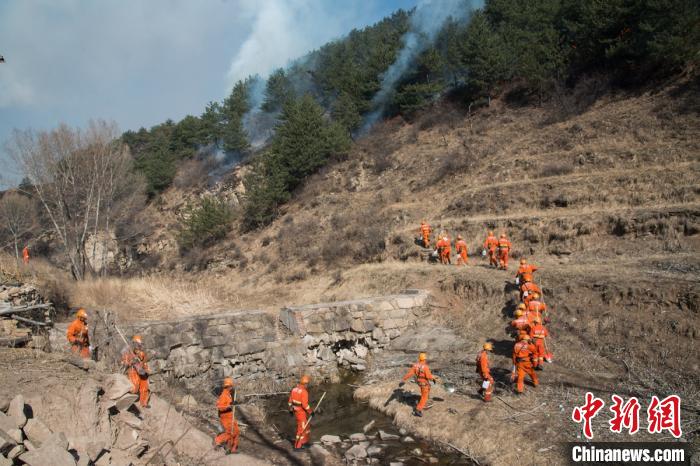 由40名武警官兵组成的突击队拎着铁锹、铁扫把、塑料水壶,跨过公路边小溪冲上山坡。 武俊杰 摄 由40名武警官兵组成的突击队拎着铁锹、铁扫把、塑料水壶,跨过公路边小溪冲上山坡。 武俊杰 摄