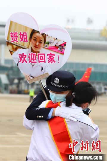 3月23日下午,一名医疗队队员与举着贴有自己照片牌子的民警妹妹相拥。 刘占昆 摄 3月23日下午,一名医疗队队员与举着贴有自己照片牌子的民警妹妹相拥。 刘占昆 摄