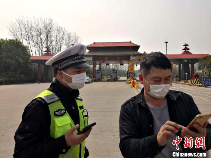 襄阳隆中高速路口,民警协助离襄人员扫码登记(摄于3月24日) 姜群 摄 襄阳隆中高速路口,民警协助离襄人员扫码登记(摄于3月24日) 姜群 摄