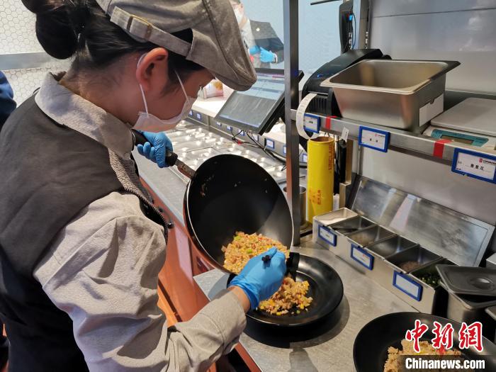 山东济南一家智慧餐厅采用智能炒菜机器人做饭,工作人员只需操作机器后,将制作好的餐食装盘,便可送上顾客餐桌。 孙宏瑗 摄 山东济南一家智慧餐厅采用智能炒菜机器人做饭,工作人员只需操作机器后,将制作好的餐食装盘,便可送上顾客餐桌。 孙宏瑗 摄